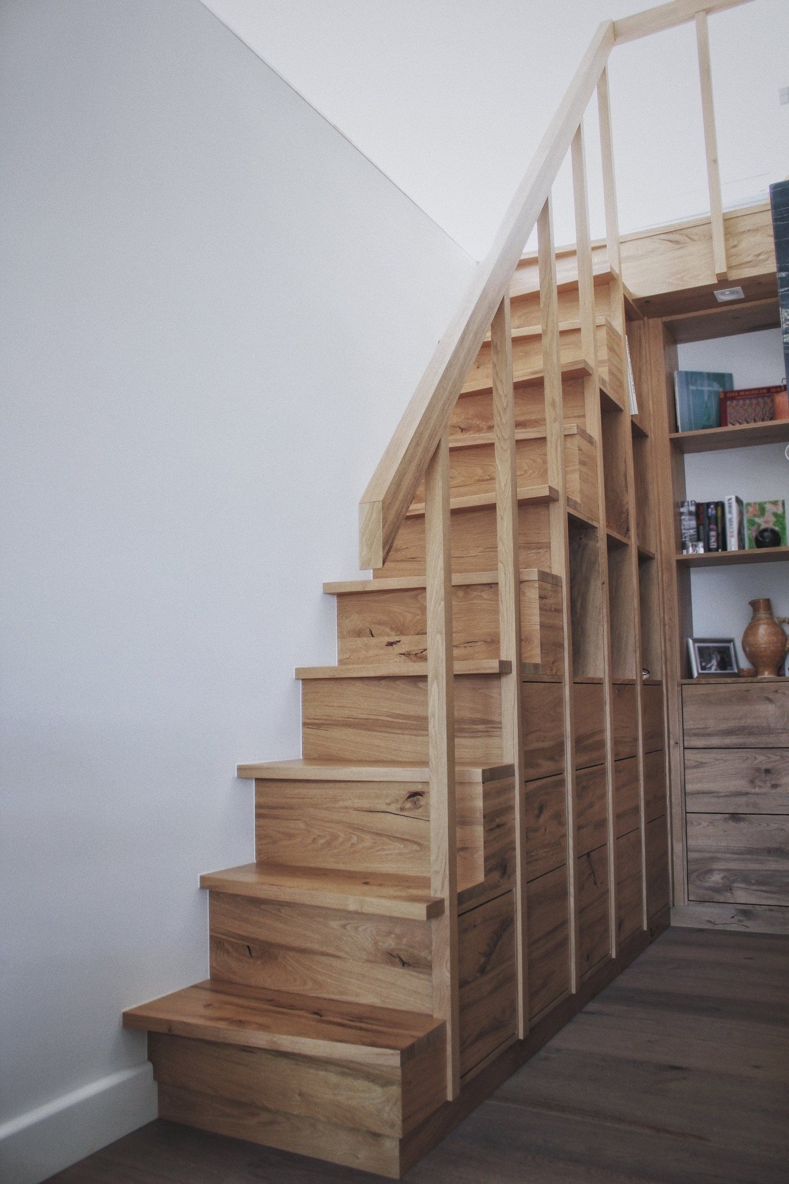 Schmale Holztreppe mit Stauraum und Regalen darunter